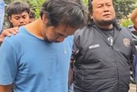 DBM (kaos biru) terduga pelaku pembunuhan keji terhadap Ibu dan Anak di Madiun ketika diamankan Ditreskrimum Polda Jatim. Foto/Ist